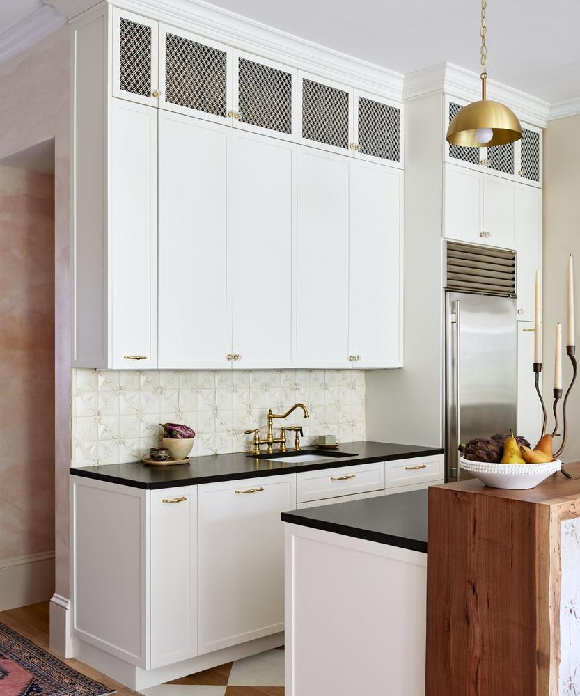 Kitchen with polished brass cabinet pulls, faucet, and warm ambient pendant lighting.