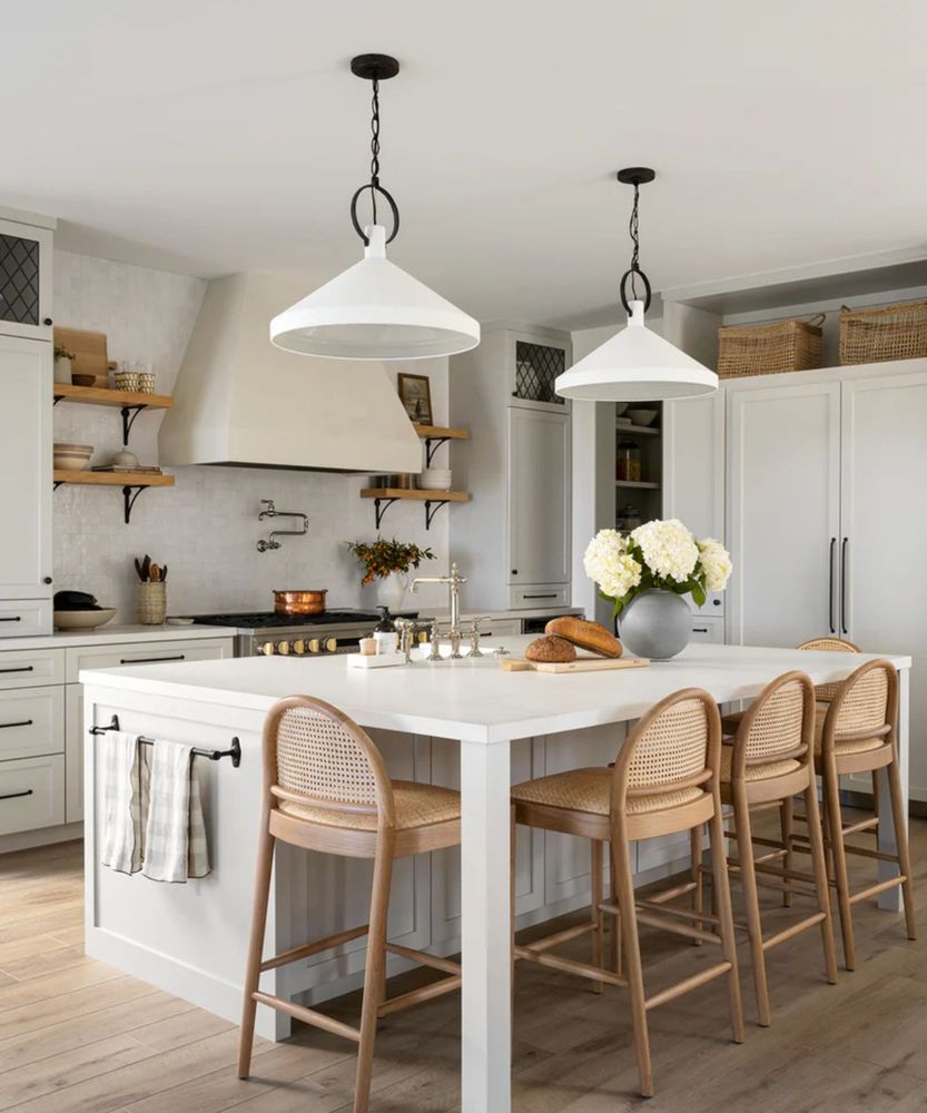 Large fireclay apron-front sink, wooden countertops, and brass wall-mounted faucet.