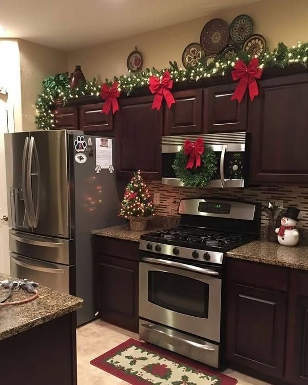 Kitchen island topped with a lush pine garland, interwoven with red satin bows and tiny white LED lights.
