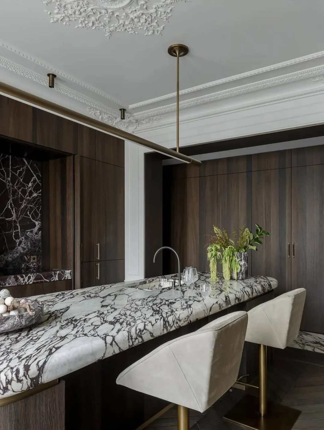 Deep navy blue kitchen island with polished brass handles, white quartz top, and cognac leather bar stools.