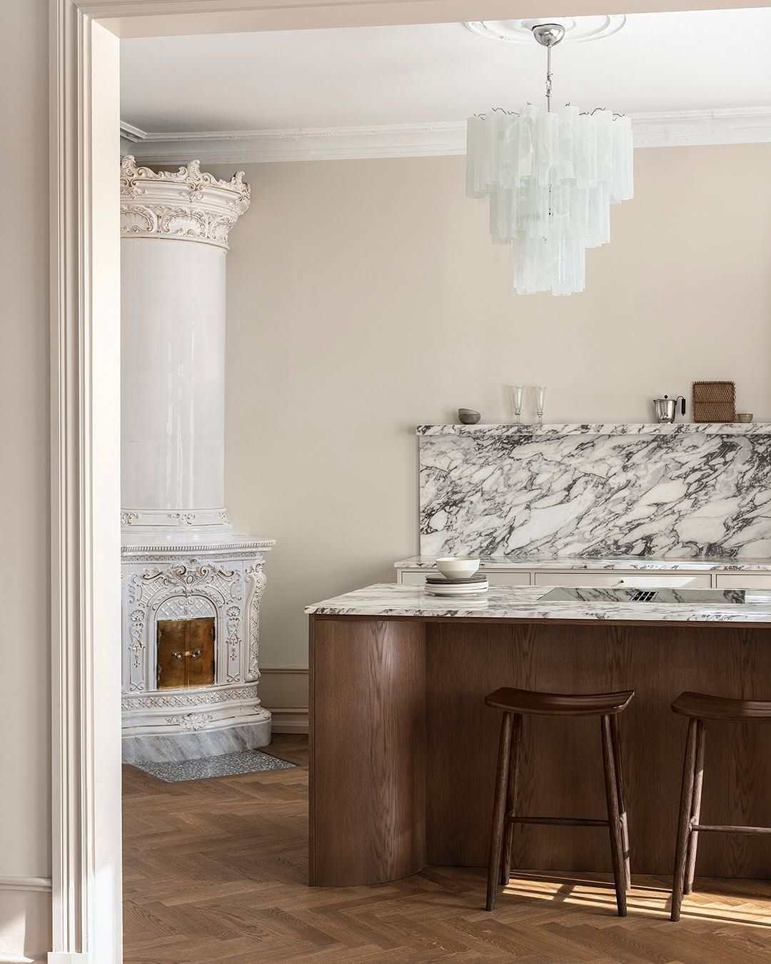 Modern curved kitchen island wrapped in fluted oak tambour paneling with a white marble top.