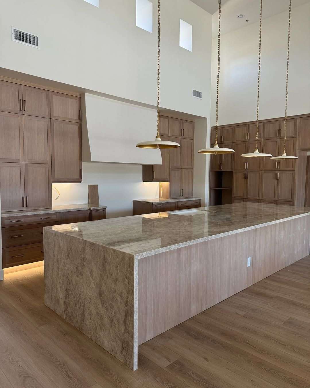 Modern moody kitchen with matte black quartz island, dark charcoal cabinets, and warm ambient strip lights.