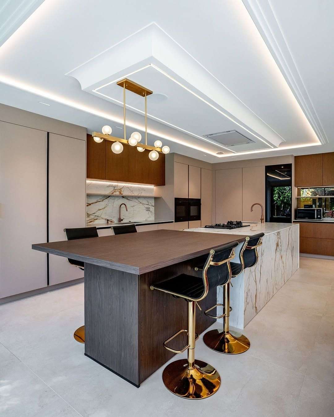 Modern kitchen island extending into a lower wooden dining table surrounded by Scandinavian wooden chairs.