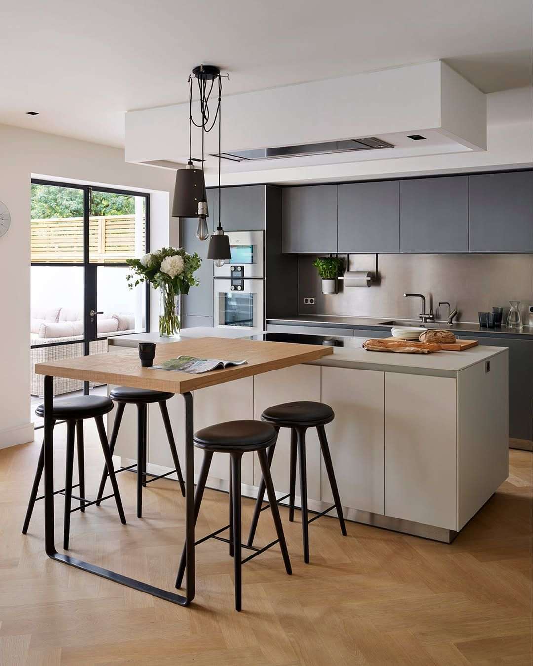 Industrial kitchen featuring a cast concrete island countertop with exposed brick walls and black metal stools.