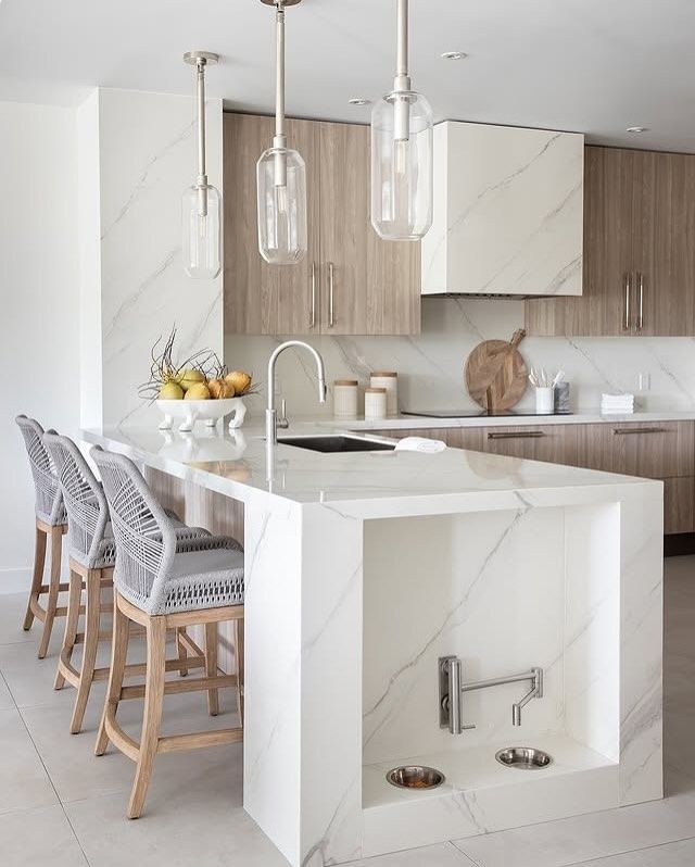 Luxurious kitchen featuring a Nero Marquina black marble island supported by polished brass frame legs.