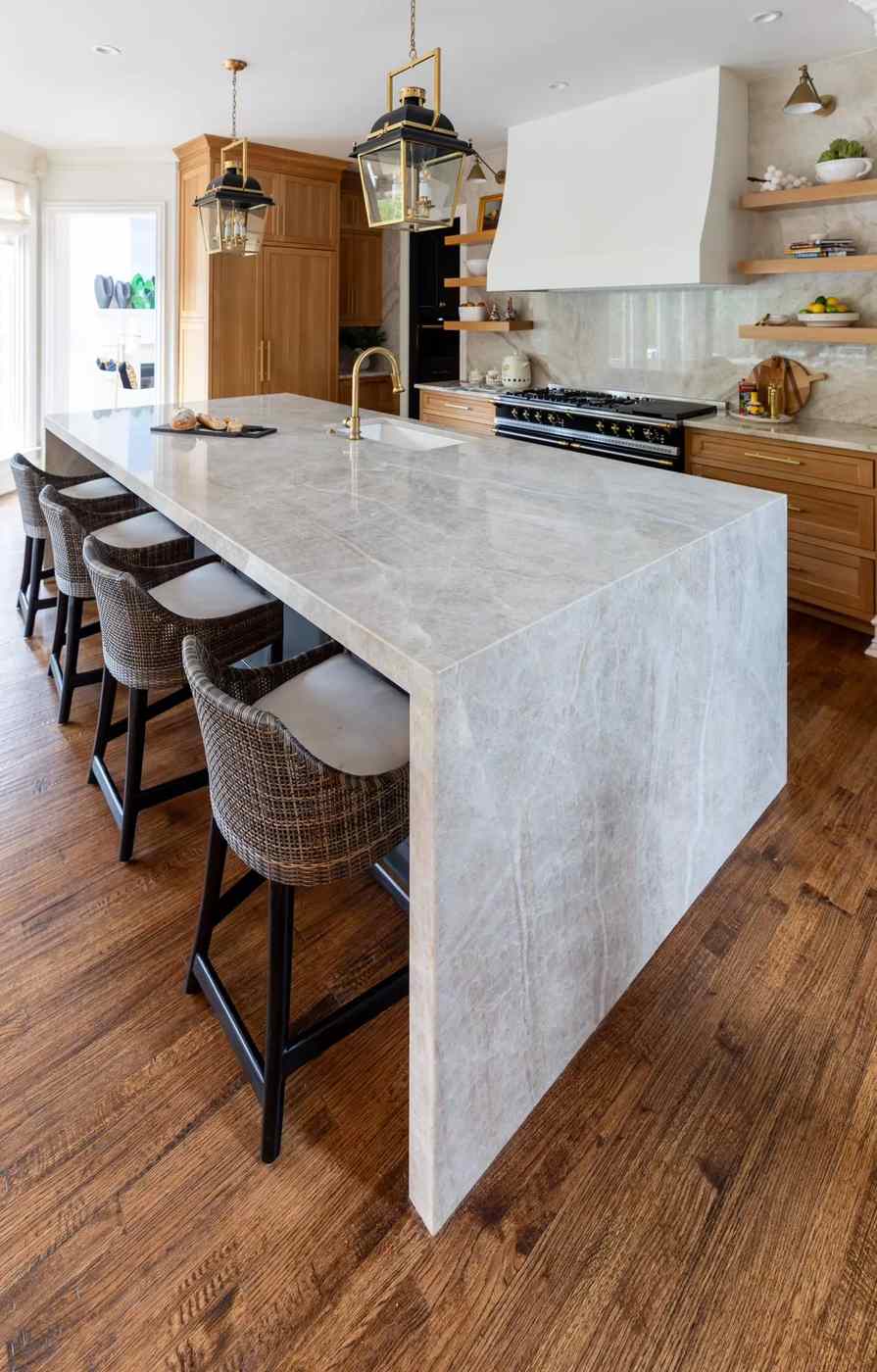 A mid-century modern kitchen island with tapered legs and warm walnut wood cabinetry.