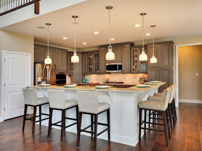A bright coastal kitchen island with white shiplap paneling and navy blue velvet stools.