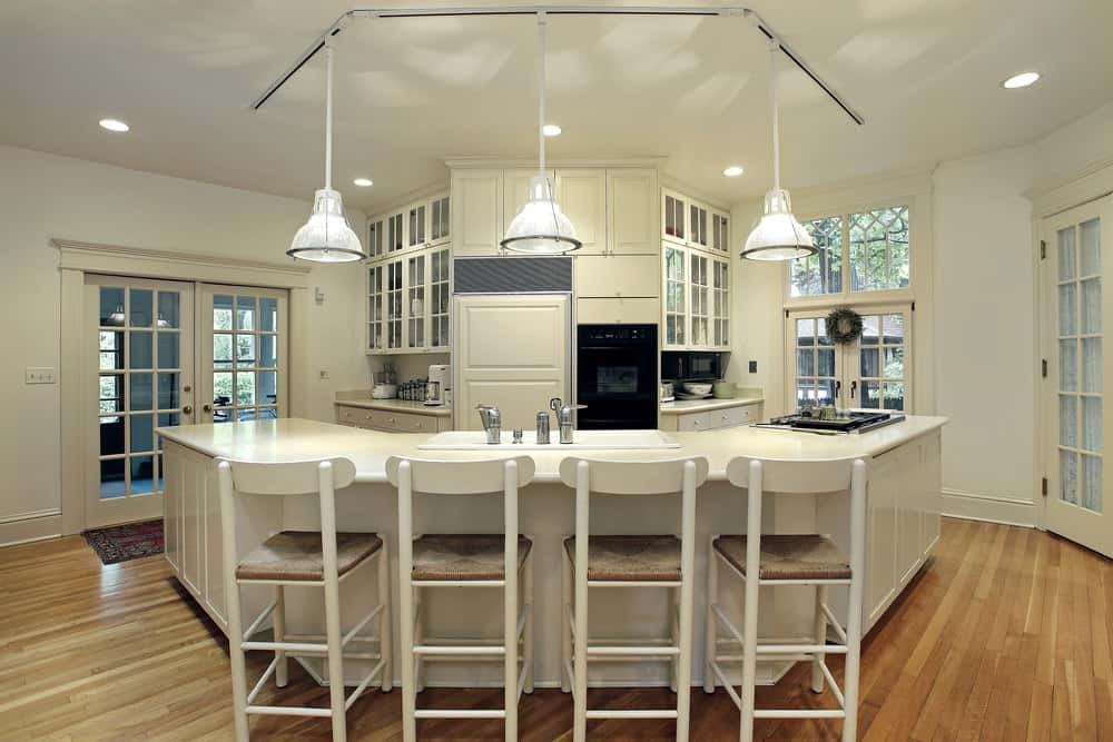 A navy blue Shaker-style kitchen island with a white quartz countertop and leather bar stools.