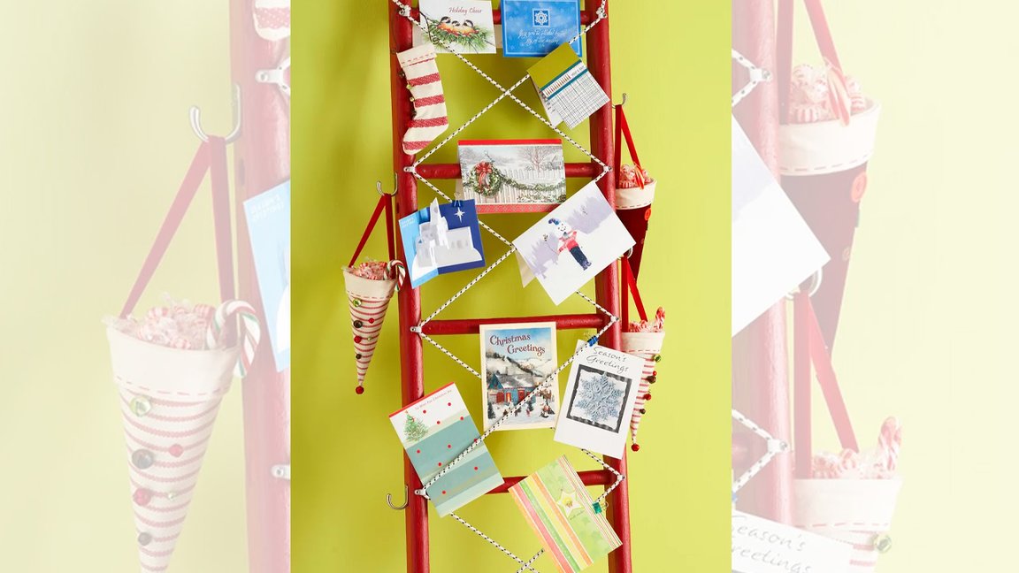 Leaning rustic wooden ladder decorated with fairy lights and holiday cards in cozy living room