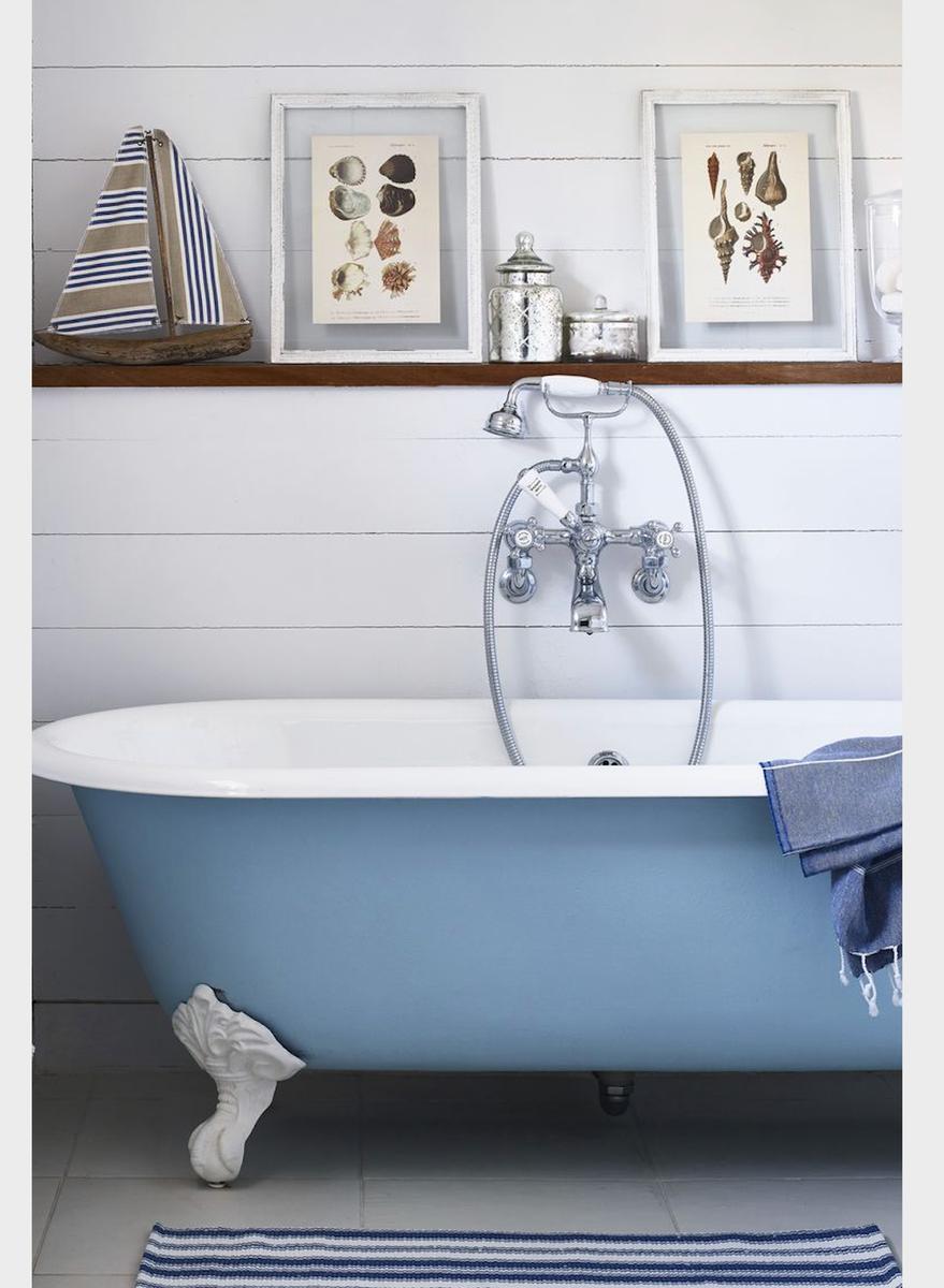 Light blue painted clawfoot bathtub set against white beadboard walls and vintage hexagon floor tiles.