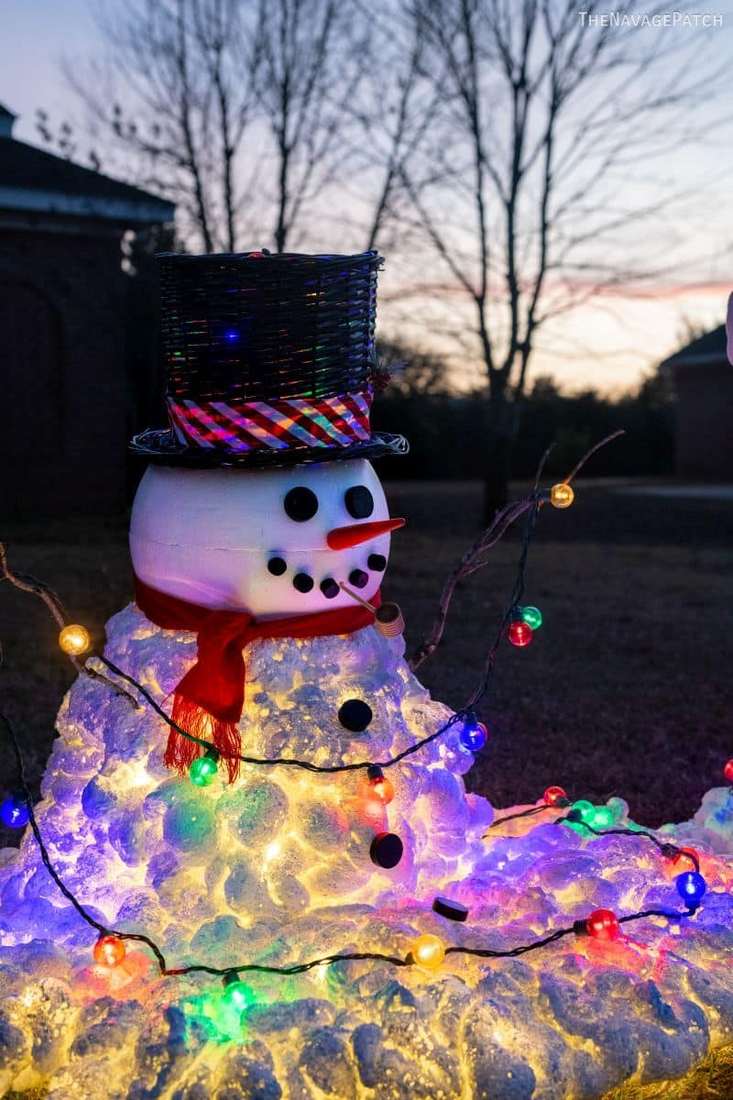 A cheerful light-up melting snowman sculpture used as festive outdoor christmas decorations.