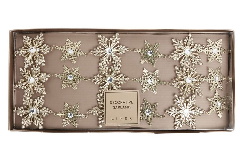 Contemporary living space mantel adorned with gold snowflake crystal garland glowing under warm ambient light