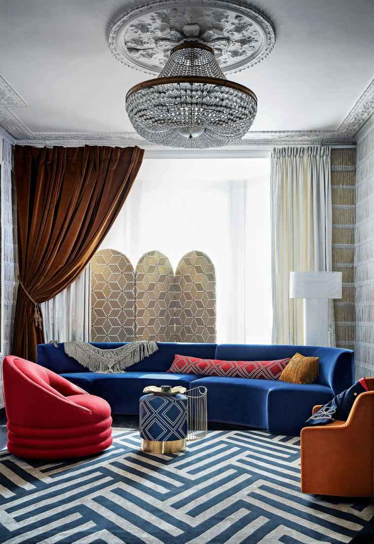 Living room featuring deep emerald velvet curtains, leather armchair, brass accents, dark moody walls.