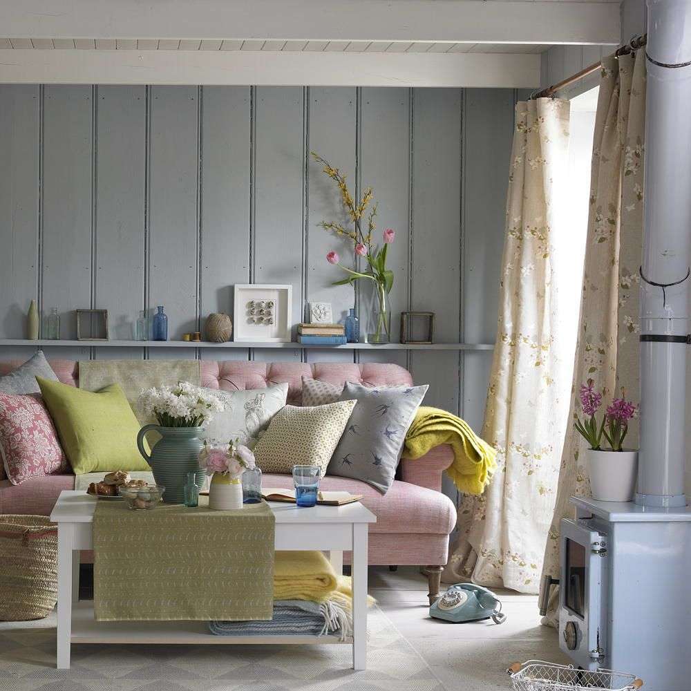 Living room with woven bamboo blinds layered behind linen curtains, comfortable sofa, light beige interior.