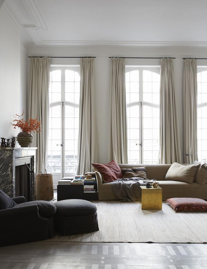 Modern industrial living room with black metal curtain rods, gray drapes, concrete floors, metallic accents.