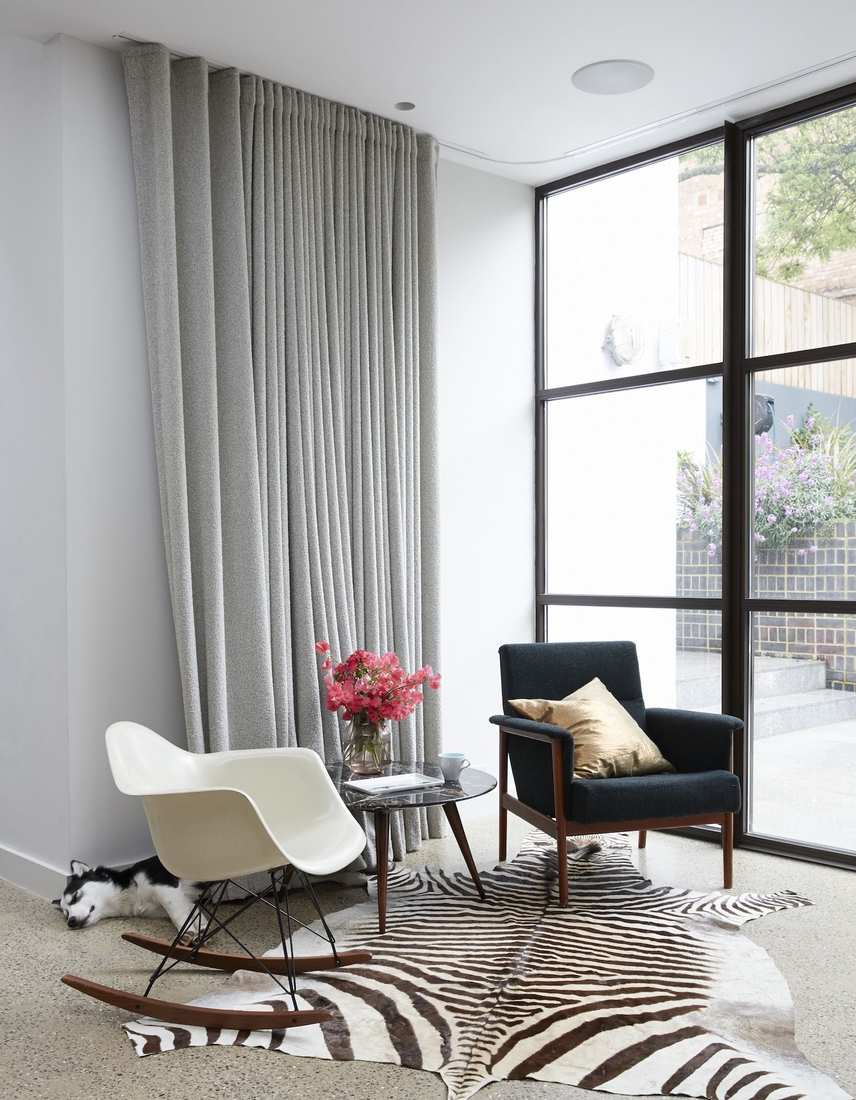 Living room with blue and white striped curtains, wicker furniture, white walls, beach-inspired decor.