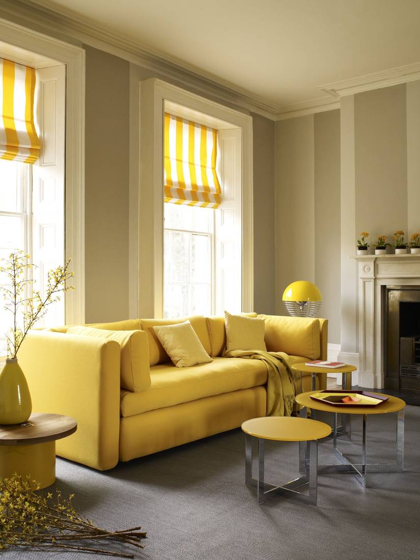 Living room with soft sage curtains, rattan furniture, plants, natural light, serene decor.