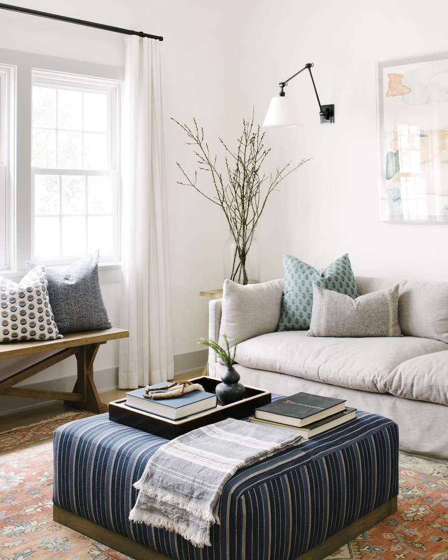 Living room with charcoal grey curtains, minimalist furniture, glass coffee table, light airy walls.