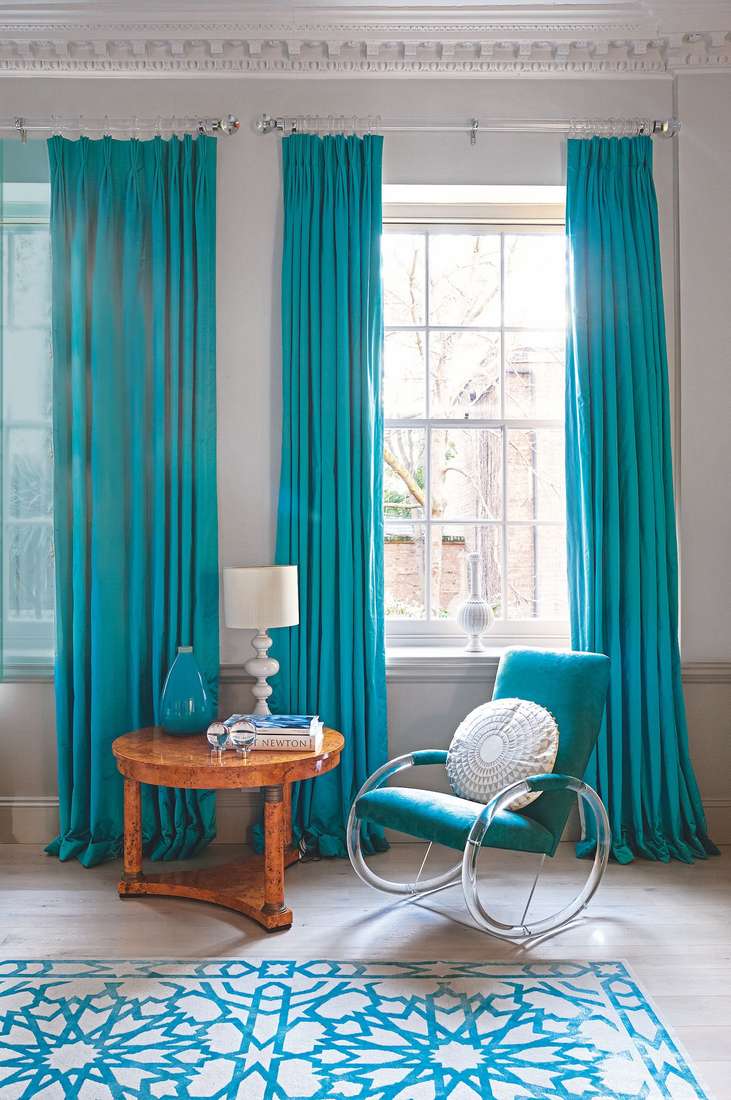 Off-white curtains with decorative tassels hanging in a bohemian styled living room.