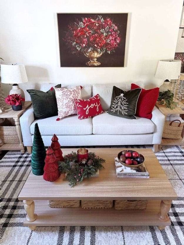 Living‑room featuring a compact fir tree with red baubles, a red velvet sofa, and a gold coffee table.
