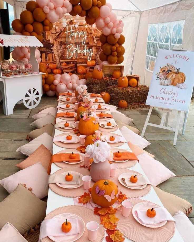 Low picnic table set with pumpkins, plaid blankets, string lights, wooden flooring, cozy autumn setting