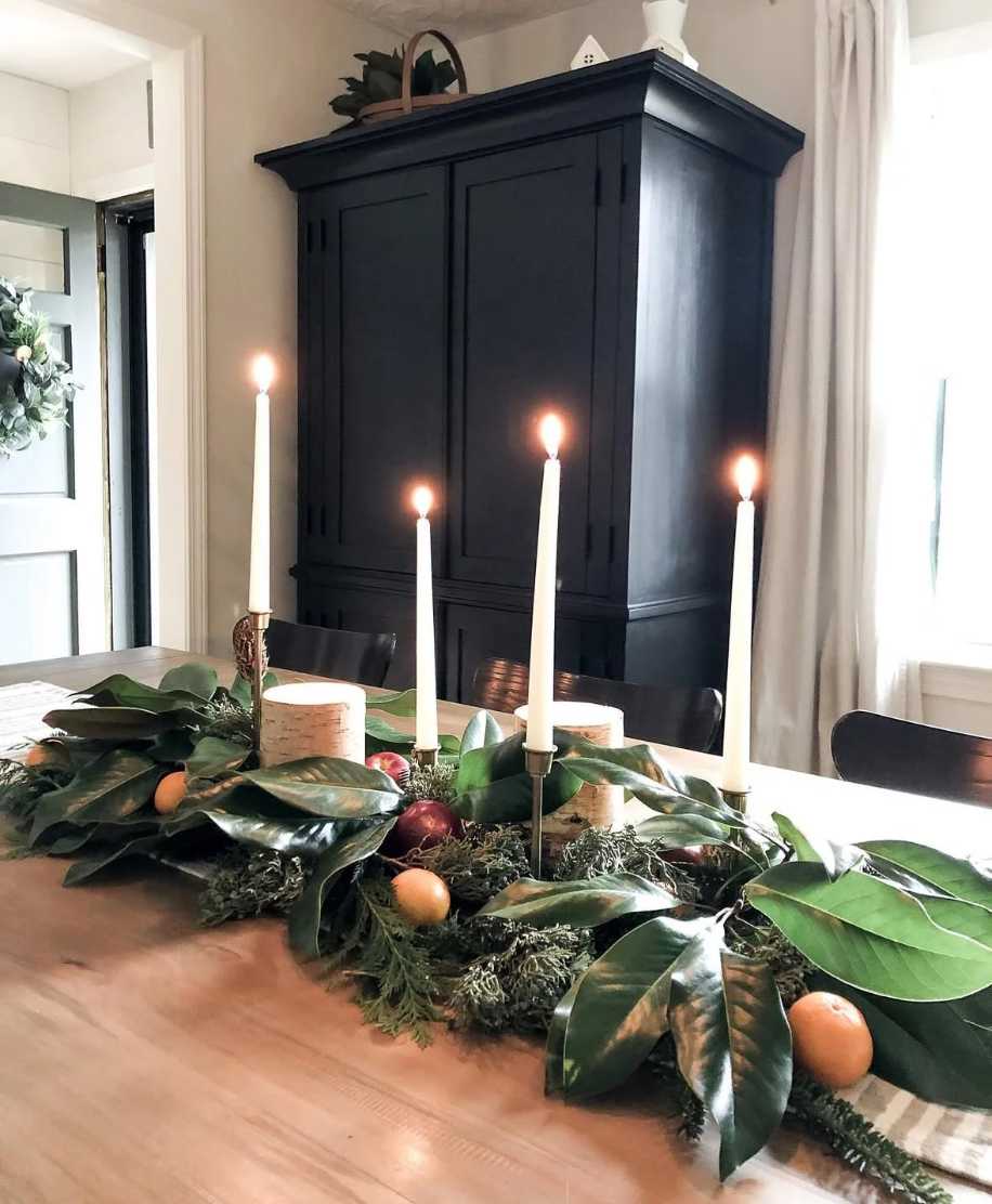 Contemporary dining, magnolia foliage garland, sliced orange and lemon, amber candles, dark wood table