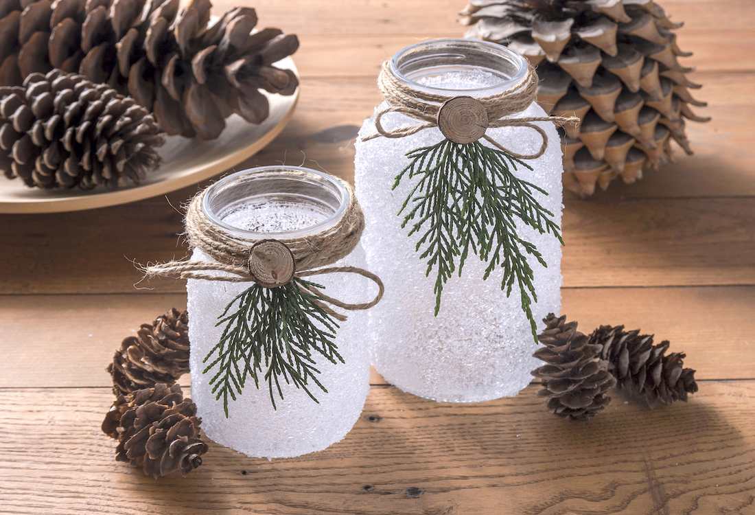 Mason jars filled with fairy lights lined up as charming outdoor christmas decorations.
