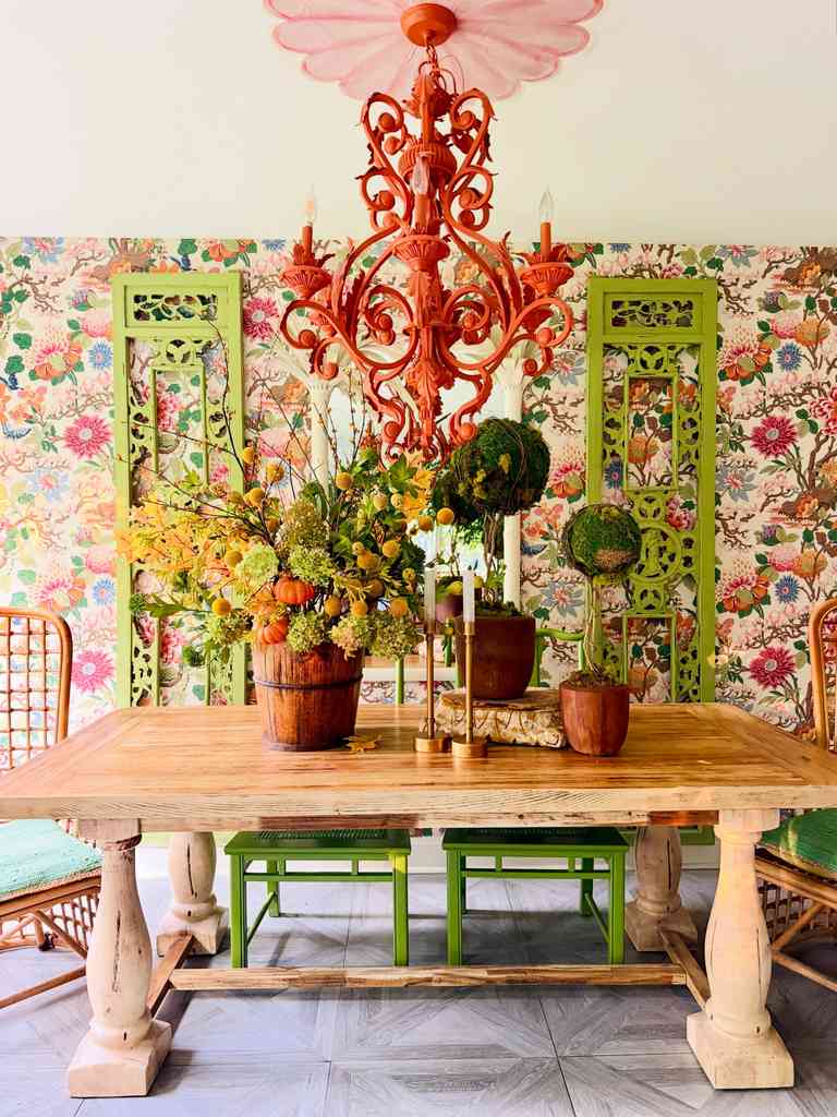 Vibrant dining room, oversized bucket centerpiece, assorted pumpkins, miniature topiary trees, mixed metal lighting.