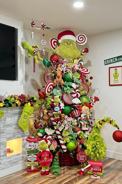 Oversized tree with many green plush toys and colorful lights in a cozy room
