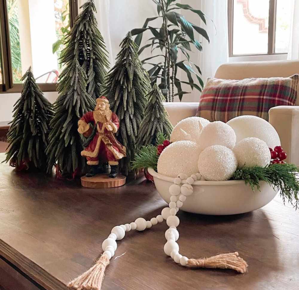 Charming Christmas coffee table decoration featuring mini fir trees and a vintage figurine of Santa Claus.