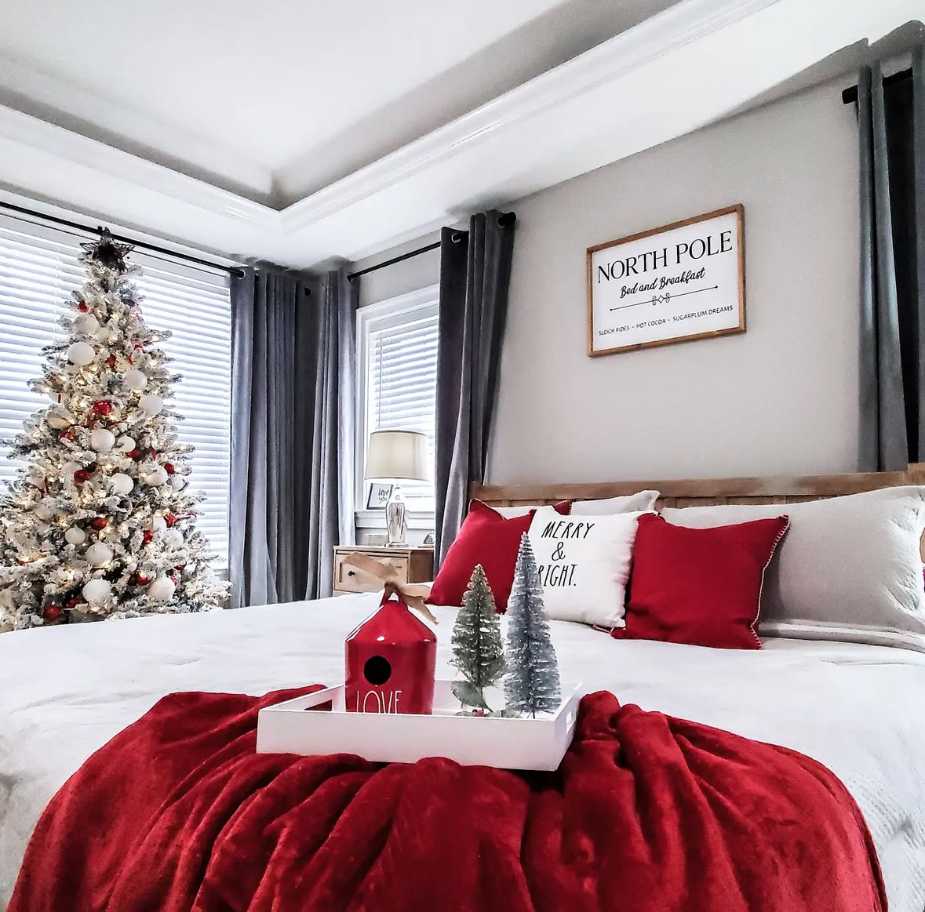 Bedroom with a small minimal tree, red bedding, white walls, and clean lines.