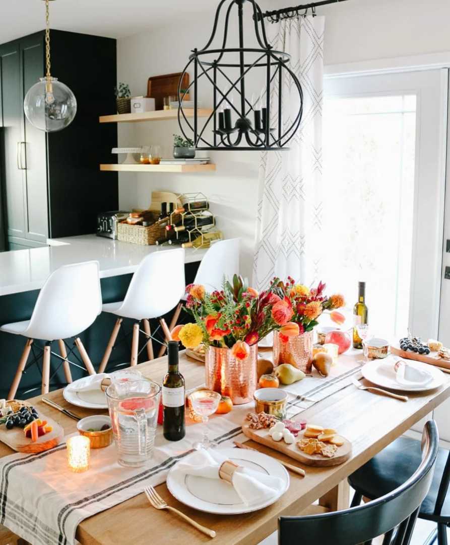 Industrial dining, copper serving board, assorted cheeses, dried figs, matte black plates, soft amber lighting