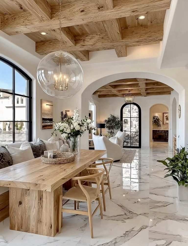 Open‑plan dining area with sleek marble table, upholstered chairs, chandelier, natural light.