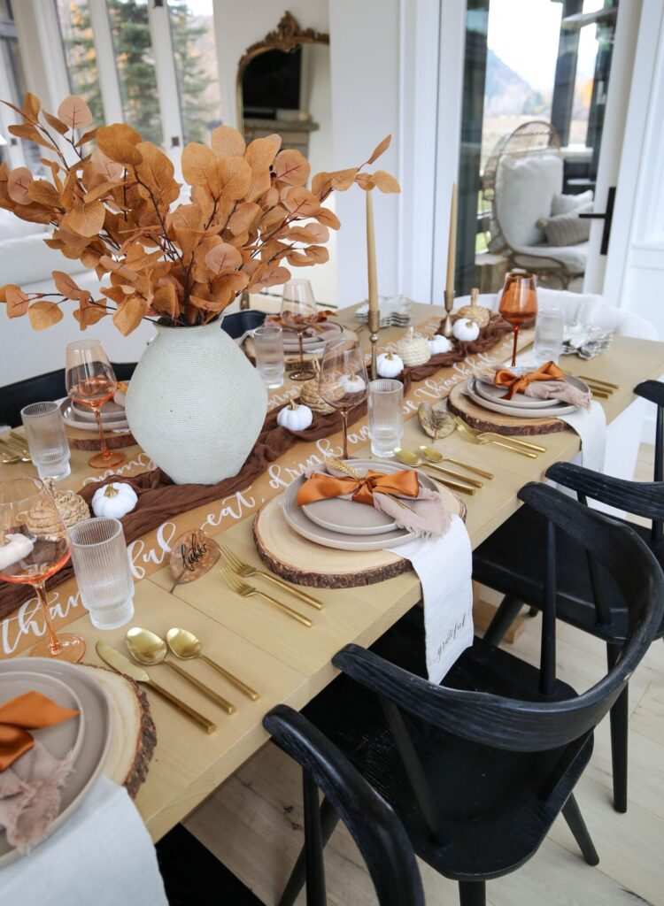 Dining table featuring wooden slice placemats, concrete chargers, linen napkins, soft white lighting