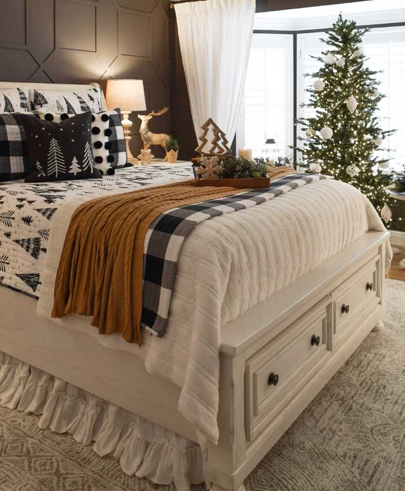 Dark bedroom with a lit Christmas tree, deep blue walls, and warm candlelight.