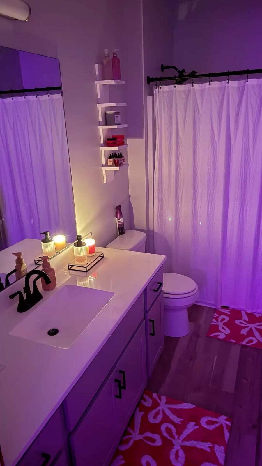 Bathroom featuring violet walls, a white freestanding tub, brushed gold fixtures, and purple LED ambient lighting.