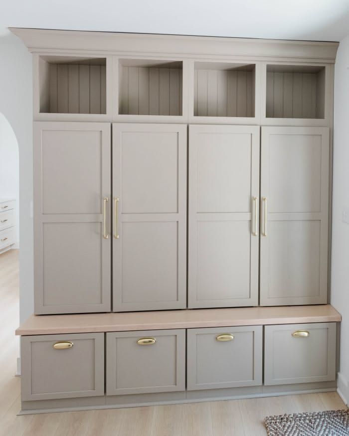 Mudroom with floor‑to‑ceiling closed lockers, matte white finish, hidden handles, soft recessed lighting