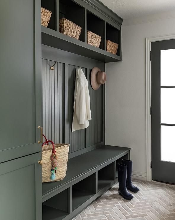 Mudroom featuring herringbone brick flooring, white bench, copper pendant, warm ambient lighting