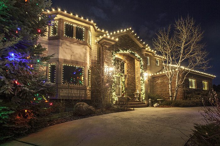 Symmetrical home facade with warm roofline lights and matching illuminated window wreaths