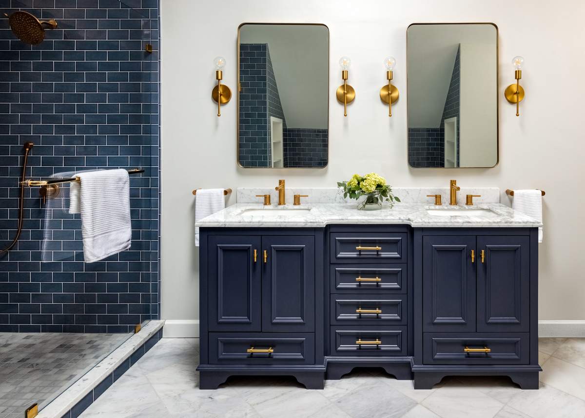 Dark navy vanity with polished chrome hardware set against glossy white subway tile walls.