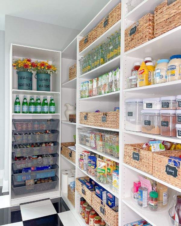 Pantry shelves featuring woven seagrass baskets, linen labels, light wood surfaces, and natural daylight.