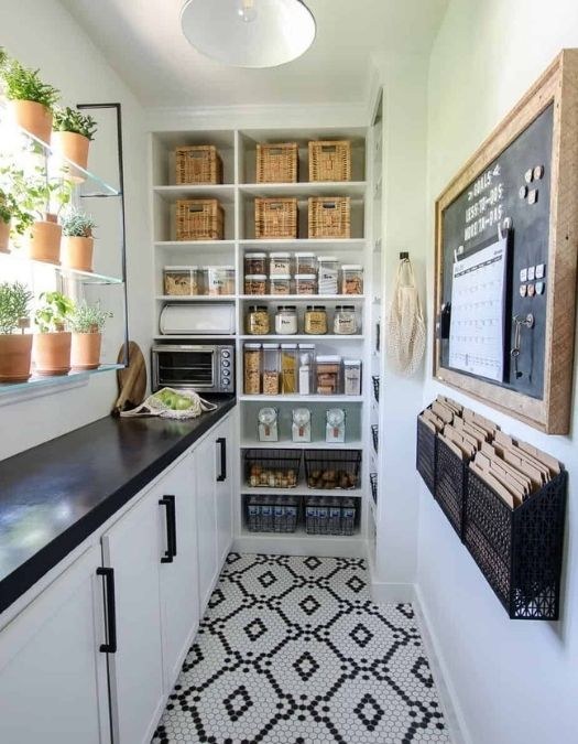 Spacious walk-in pantry with marble countertops, brass hardware, custom cabinetry, and chandelier lighting.