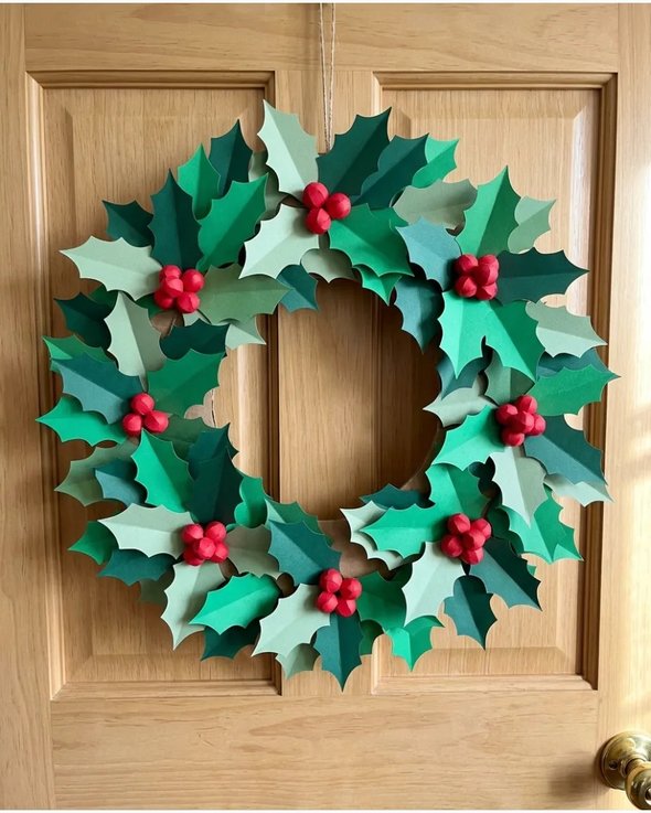Paper holly wreath on white wall with red berries