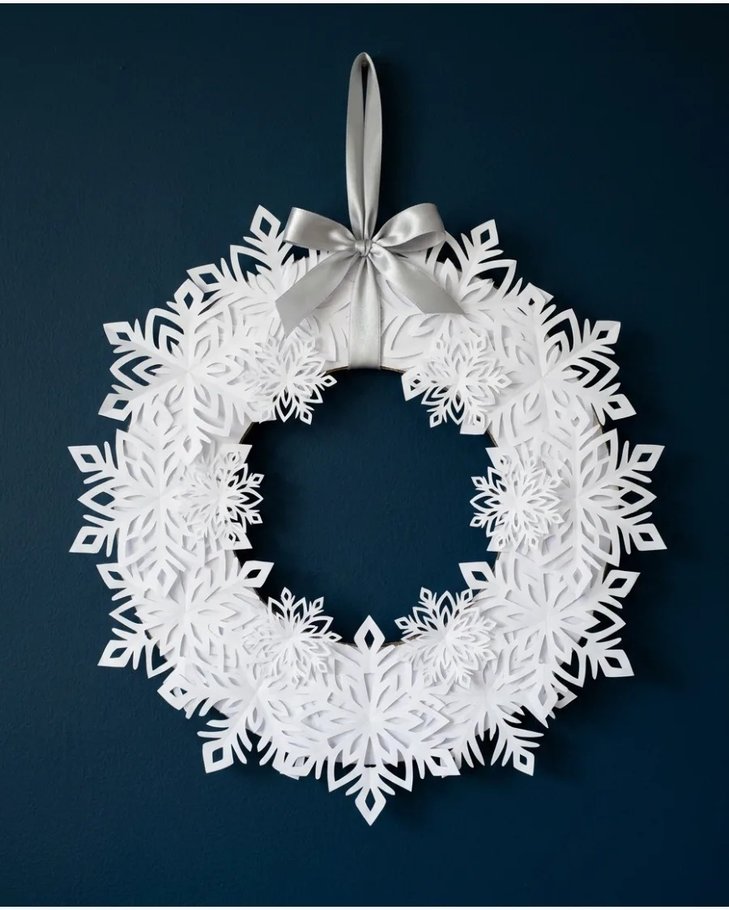 Paper snowflake wreath on white wall with blue accents
