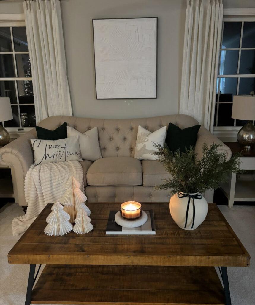 Creative Christmas coffee table centerpiece featuring folded paper trees, pine foliage, and a flickering candle.