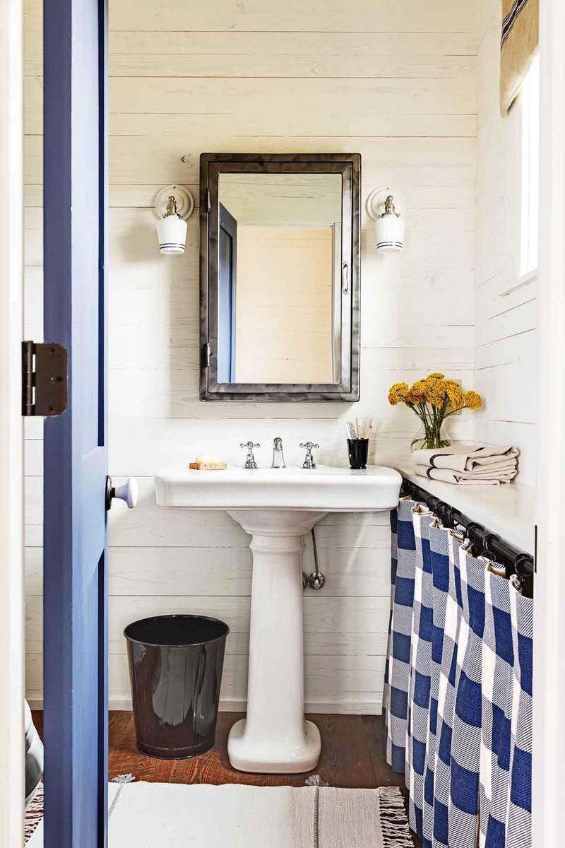 White pedestal sink paired with soft blue gingham cafe curtains and vintage brass accessories.