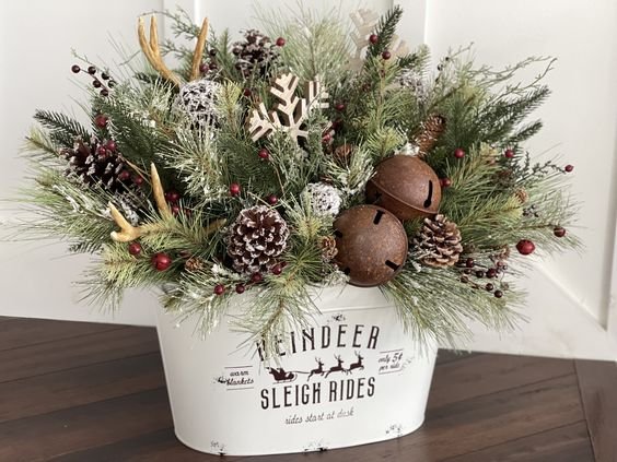 Metal bucket filled with pinecones and red berries on a rustic shelf.