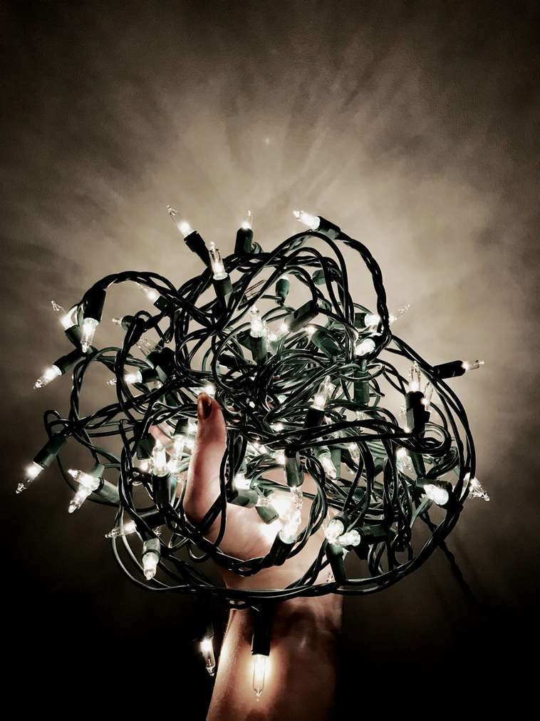 Heavy black extension cords dragging down an elegant staircase garland and banister decor.