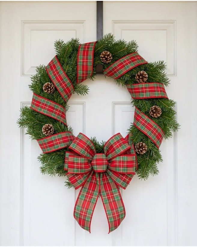 Plaid ribbon wreath on white door with warm lighting