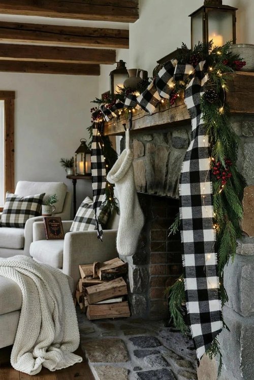 Mountain lodge living room fireplace featuring evergreen pine garland tied with classic red plaid ribbon